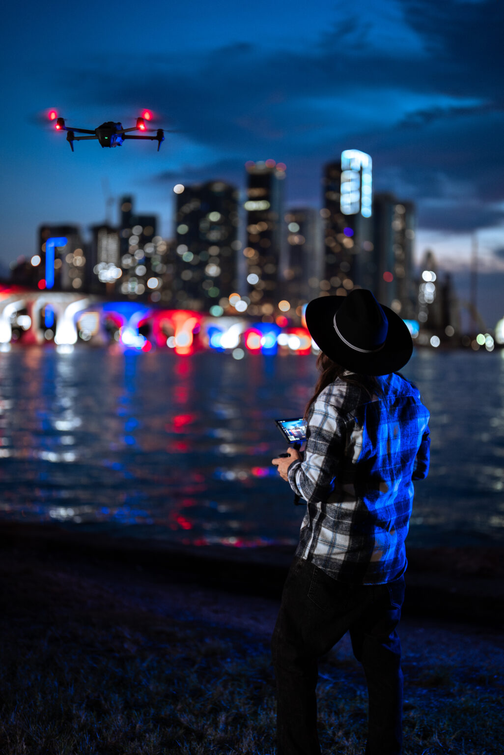 Matthew Hoyos flying a drone at night over Biscayne Bay with the Miami skyline behind him