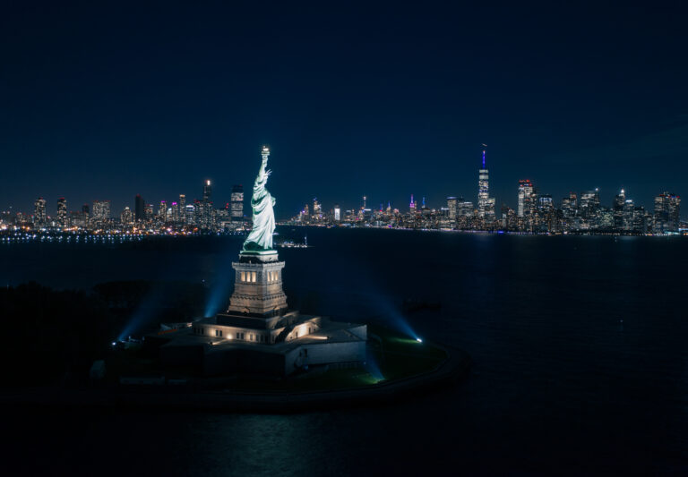 Statue of Liberty at night with the Manhattan skyline | Matthew Hoyos