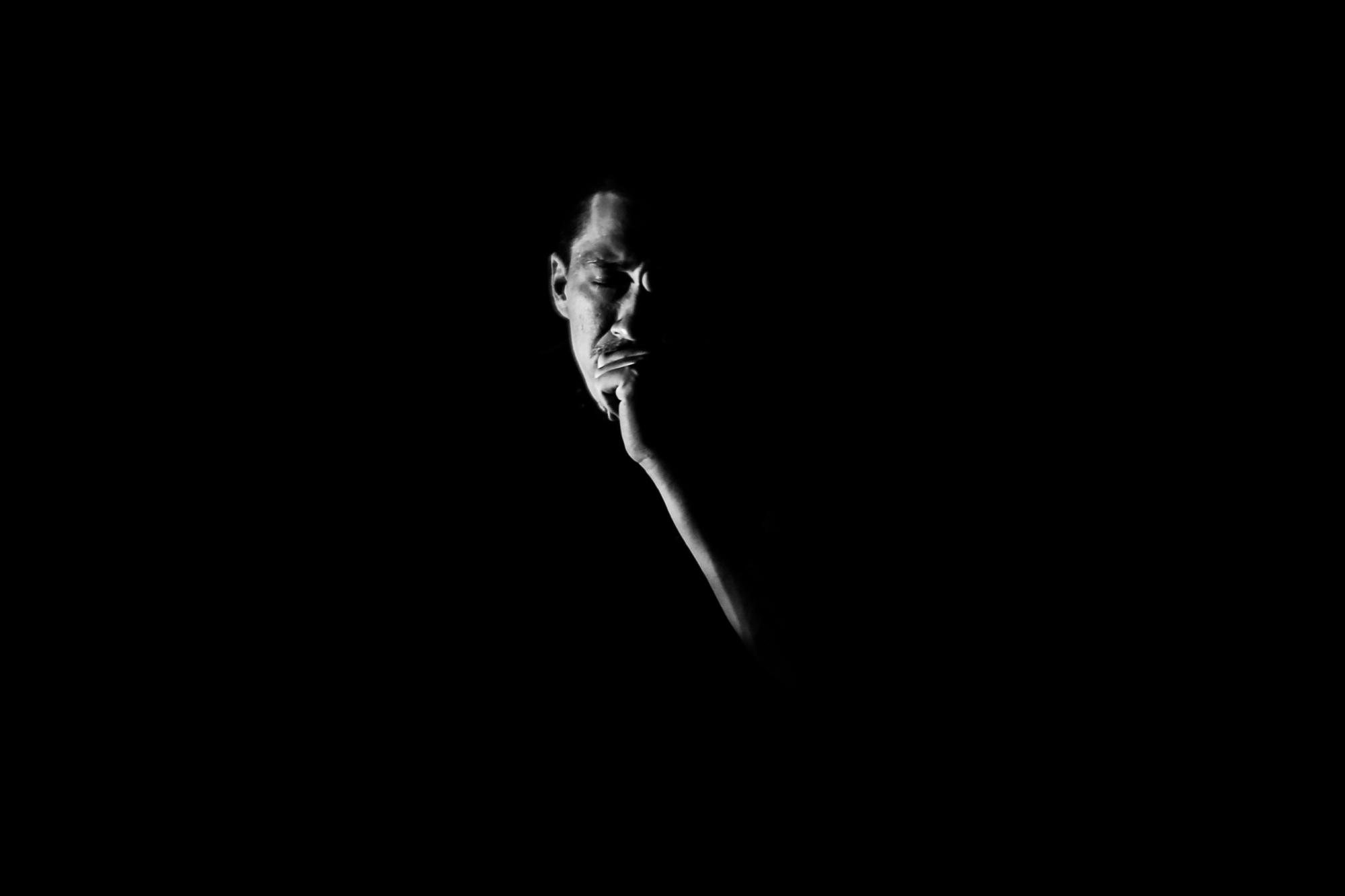 Low-key self-portrait of Matthew Hoyos emerging from shadow